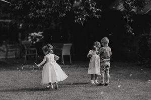 Black and white landscape photograph of people gathering together at an outdoor event in a park setting.