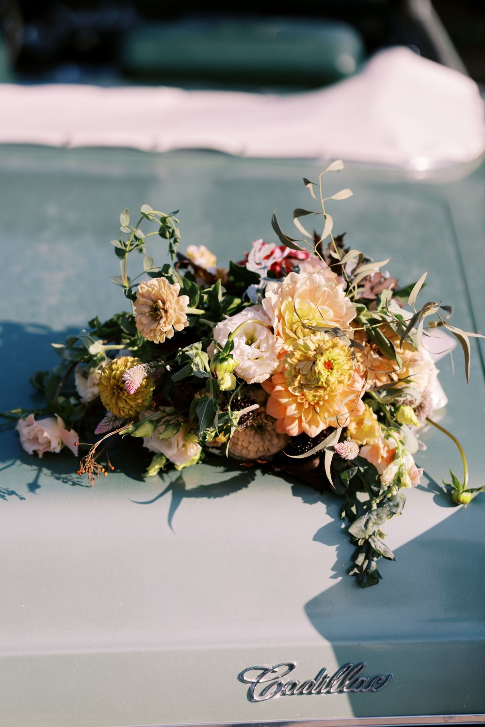 Romantic pastel floral arrangement on hood of vintage Cadillac.