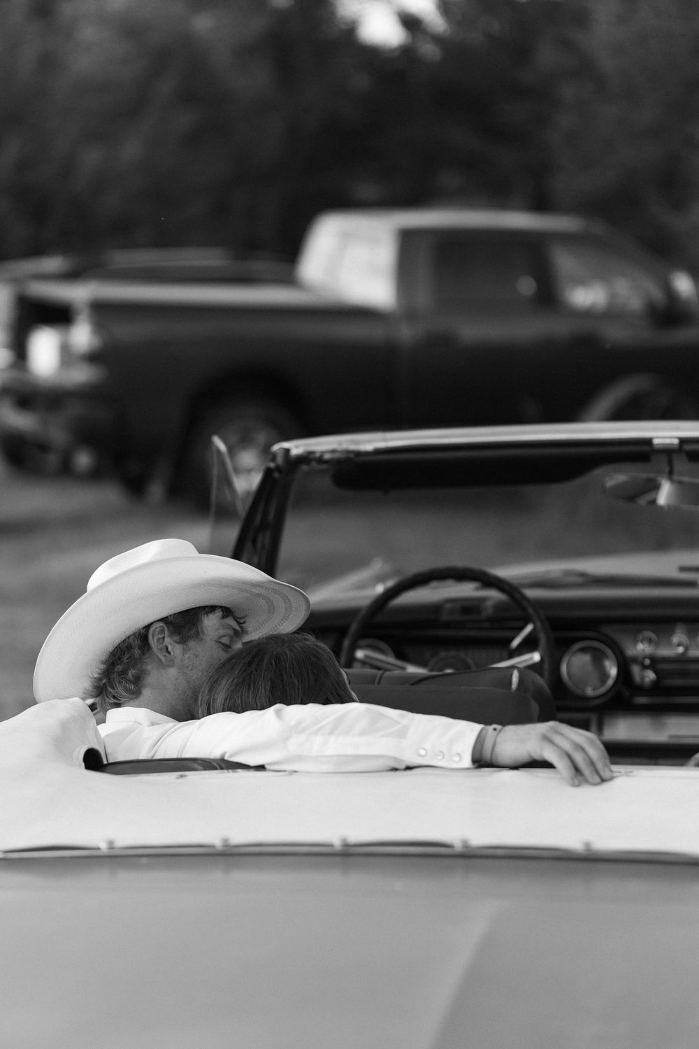 Person wearing a cowboy hat relaxes in a classic convertible car.