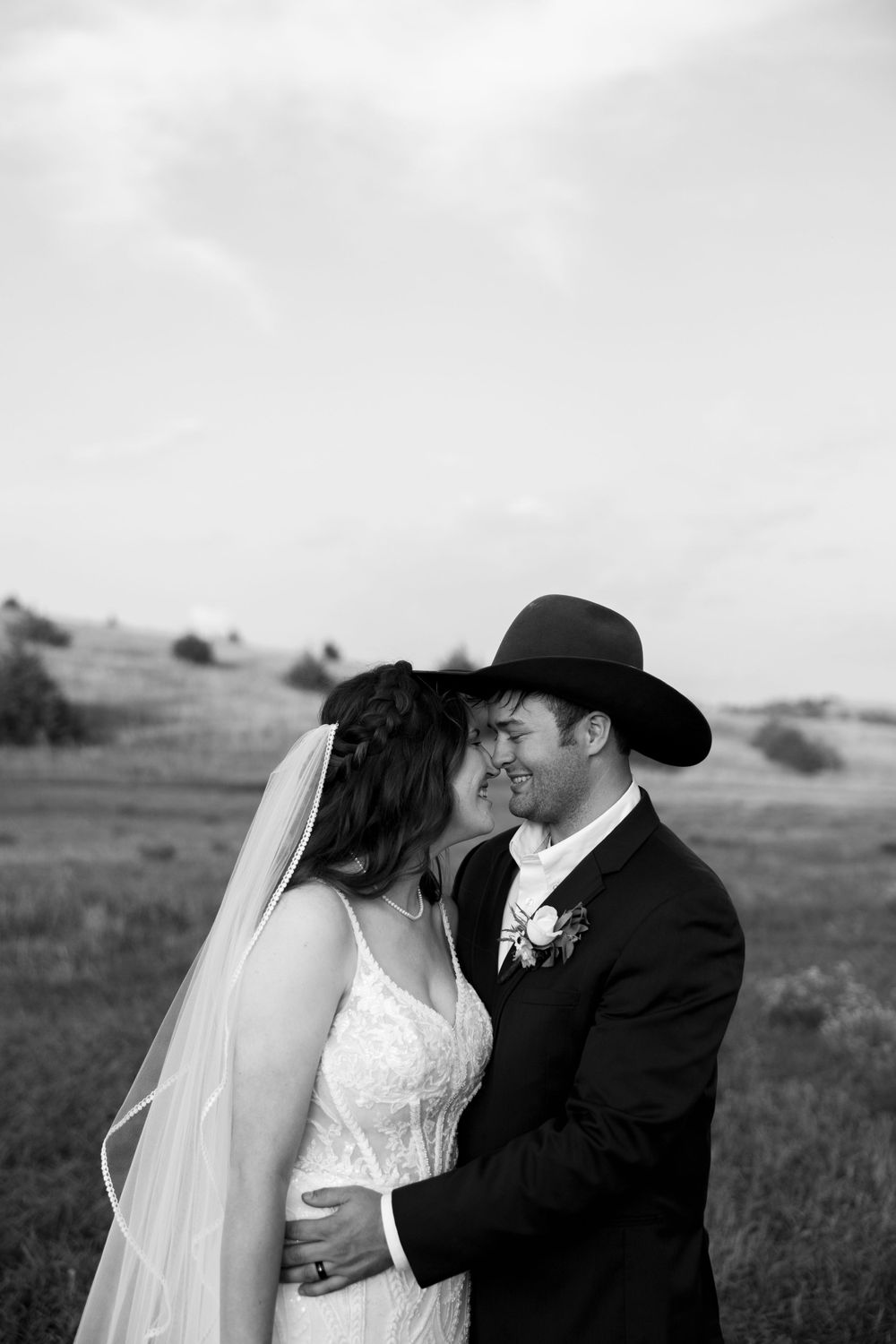 An emotional black and white wedding portrait capturing a tender embrace in nature.