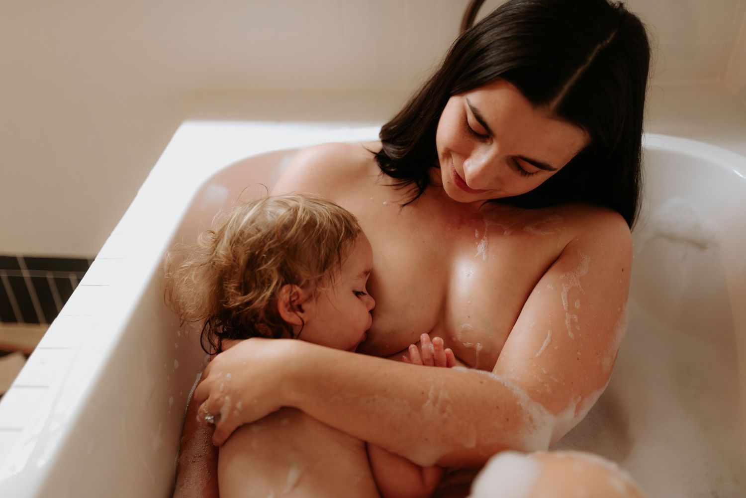 Candid bathroom scene showing nurturing moment between parent and child.