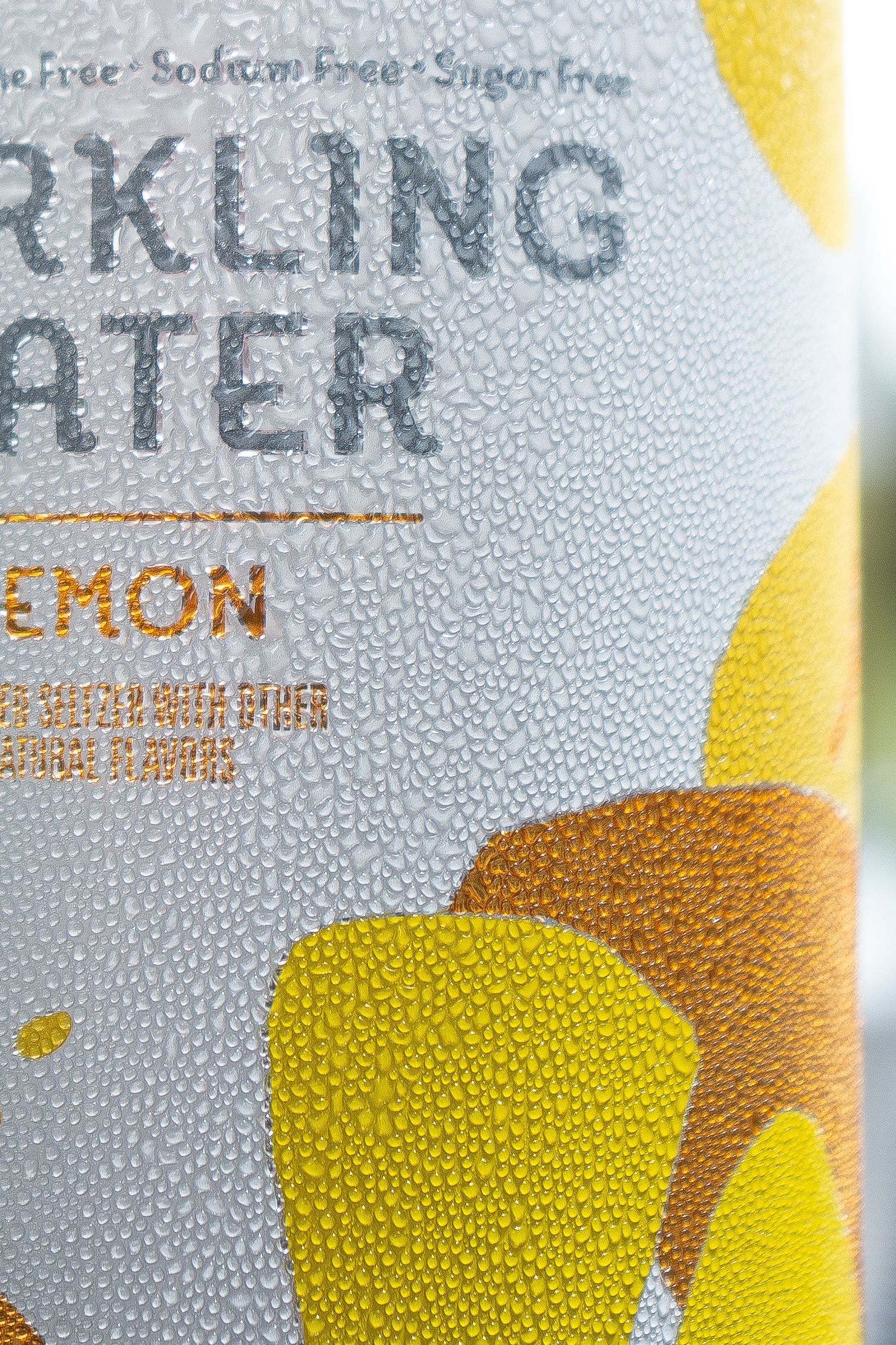 White and yellow branded sparkling water can with water droplets on the surface.