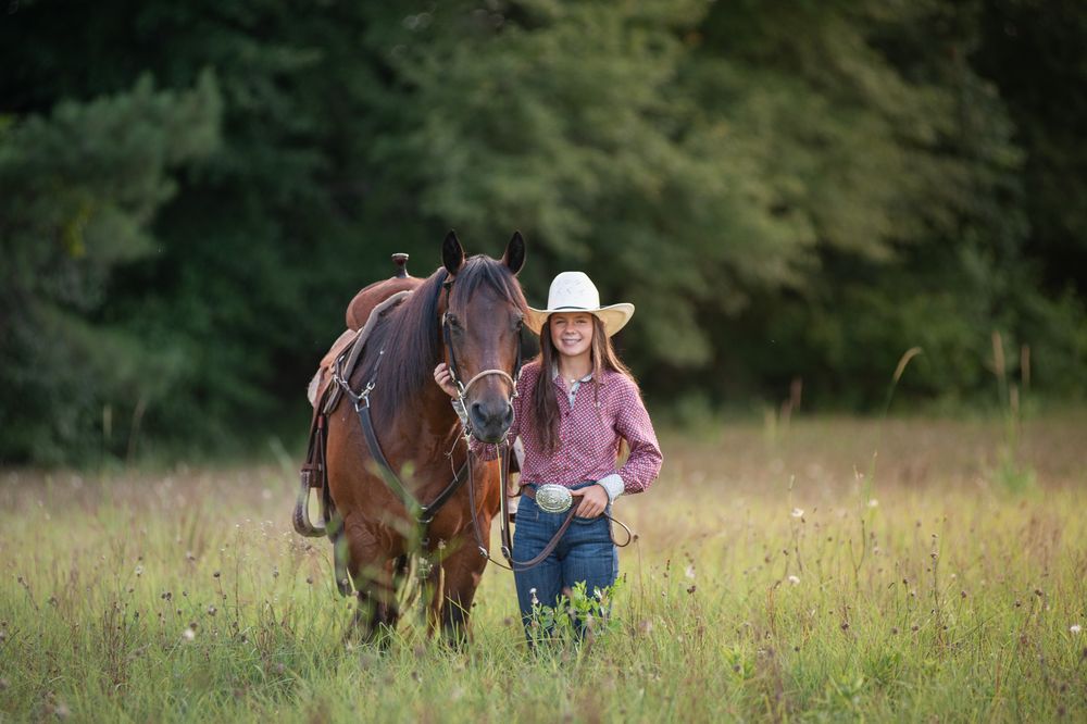 Horse and rider walking through a wildflower meadow during golden hour.