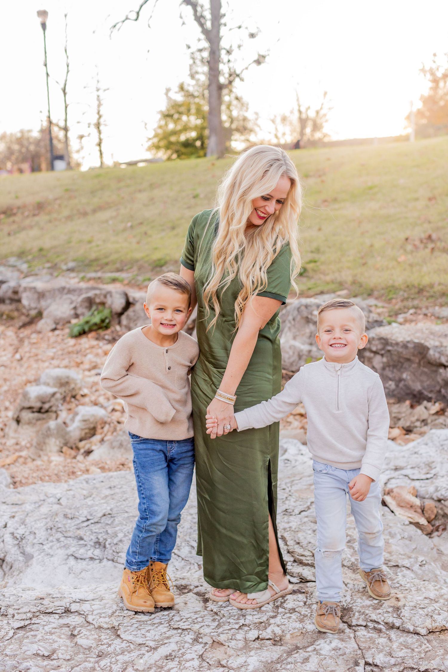 Family enjoying playful moments together on rocky terrain during golden autumn sunset.