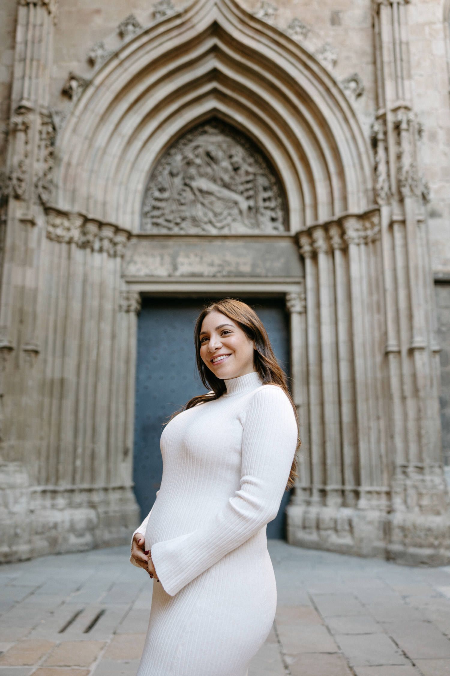 Maternity photo session in front of a historic stone church with ornate gothic archways.