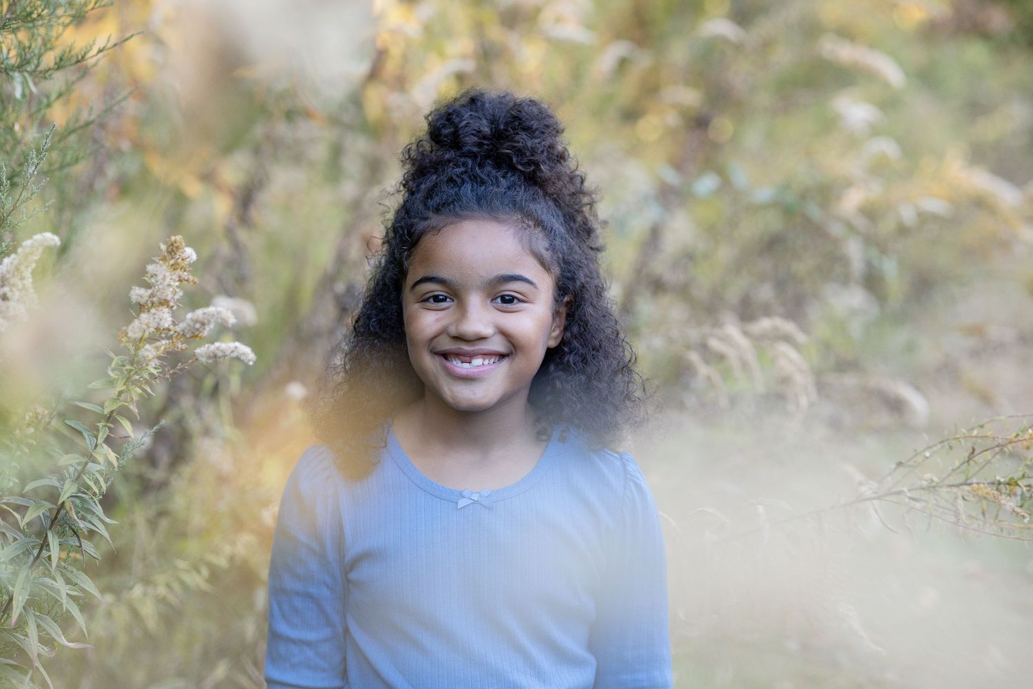 Springfield, IL family photographer captures a young girl amongst fall flowers during a photo session in Central, IL