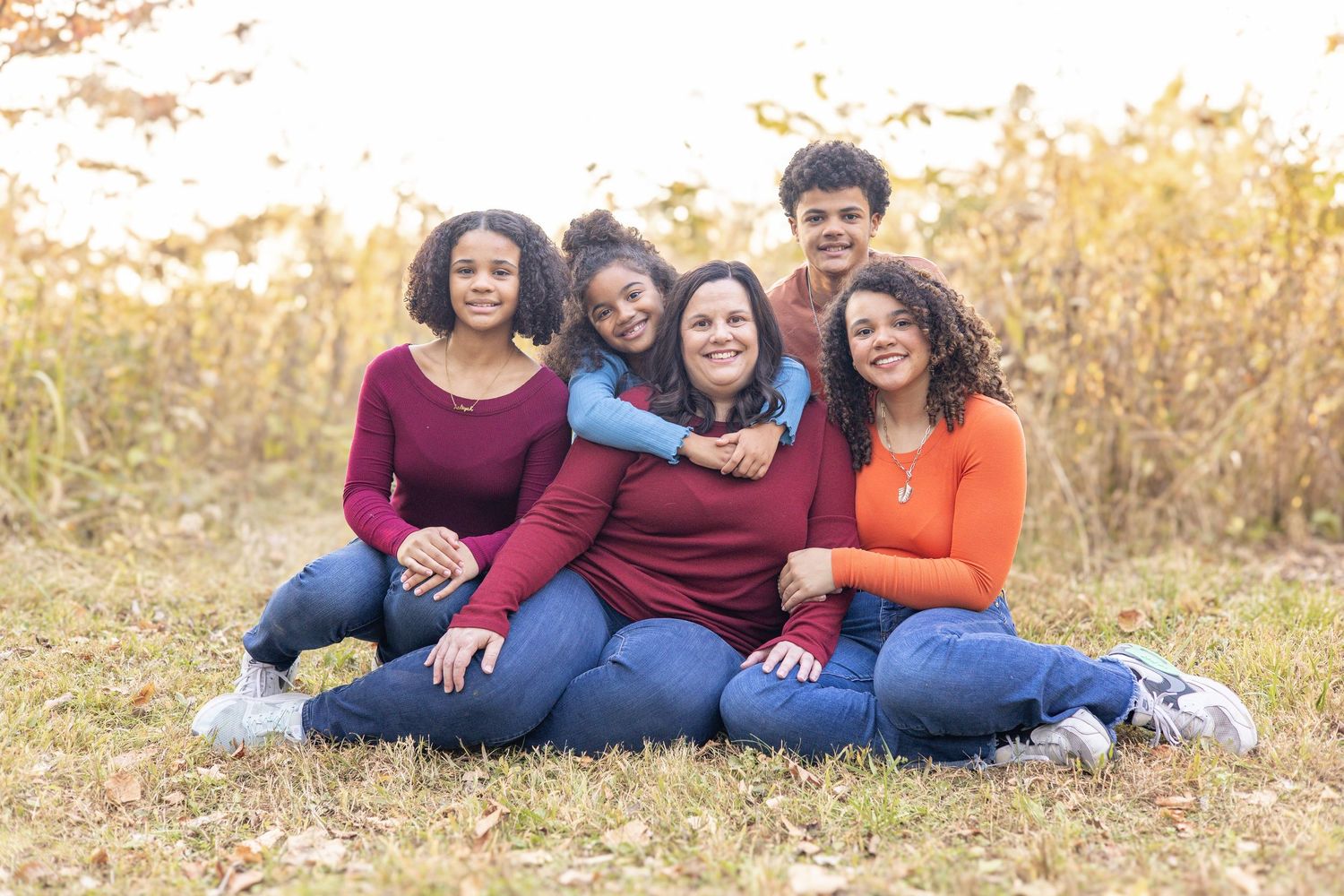 Springfield, IL family photographer captures a family sitting together in front of a fall flower field during a photo session in Central, IL