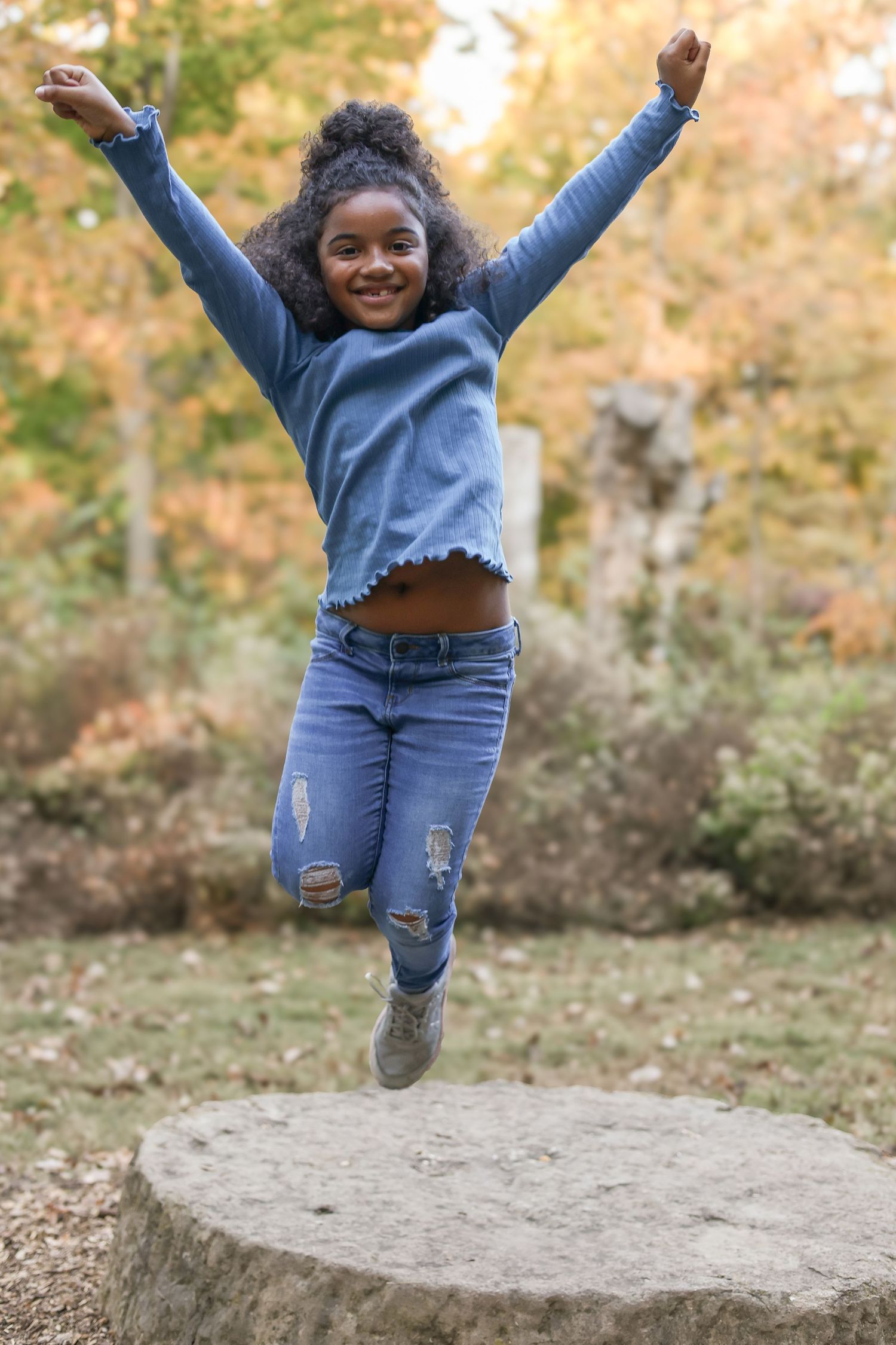 Springfield, IL family photographer captures a young girl jumping off a stump during a photo session in Central, IL