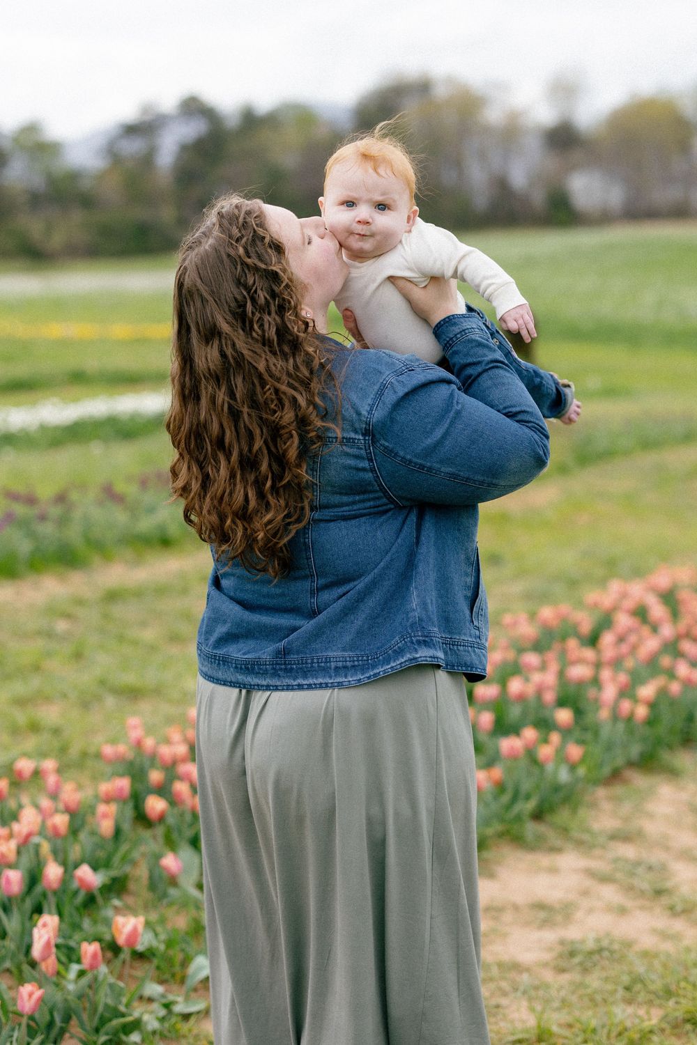 A tender moment shared between parent and child in a spring tulip field with blooming pink flowers.