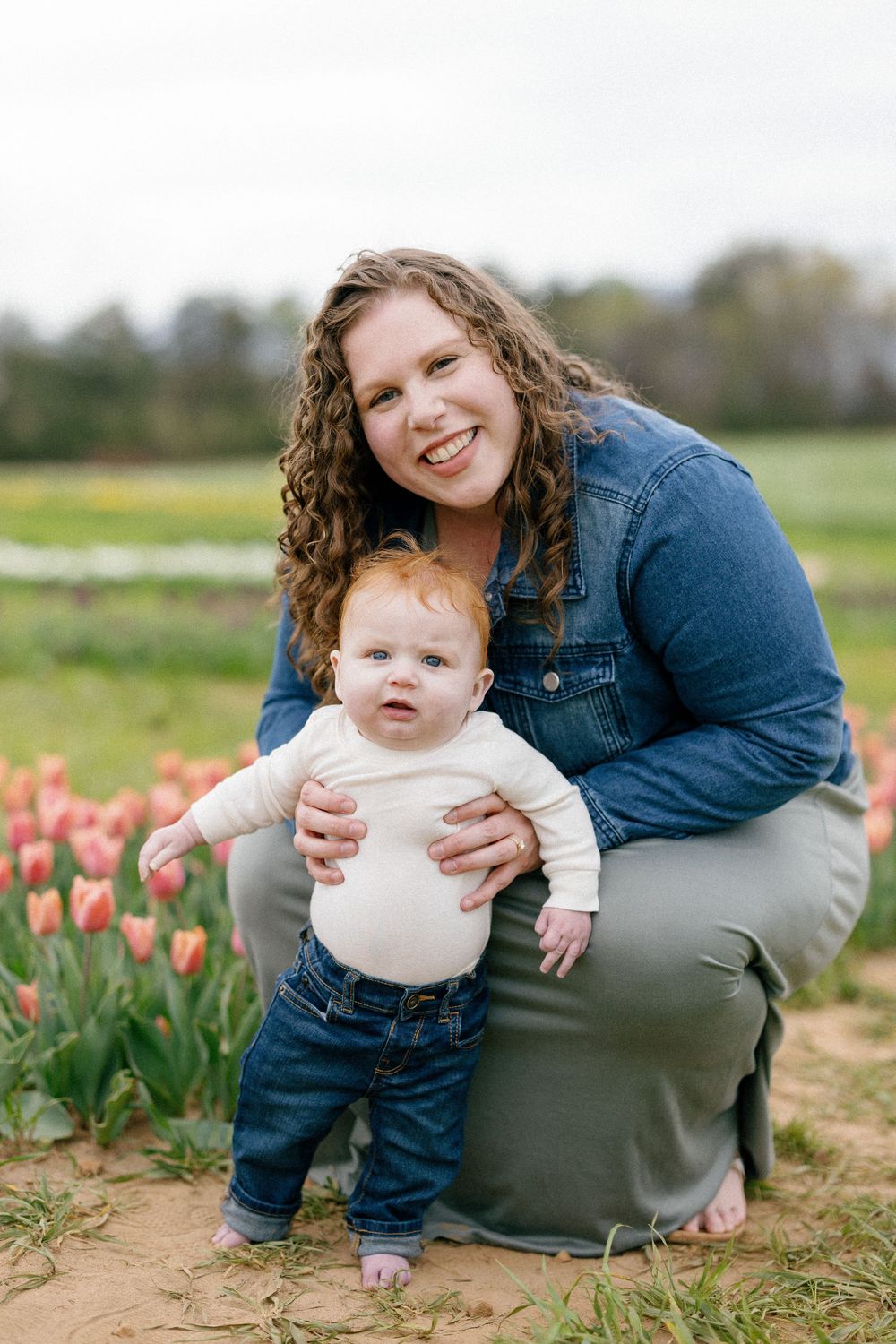 A family enjoying a spring day together in a field of blooming orange tulips.