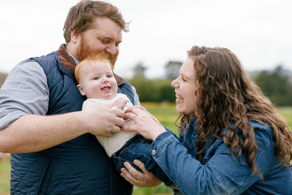 A happy family shares joyful moments together outdoors in a grassy field during sunset.
