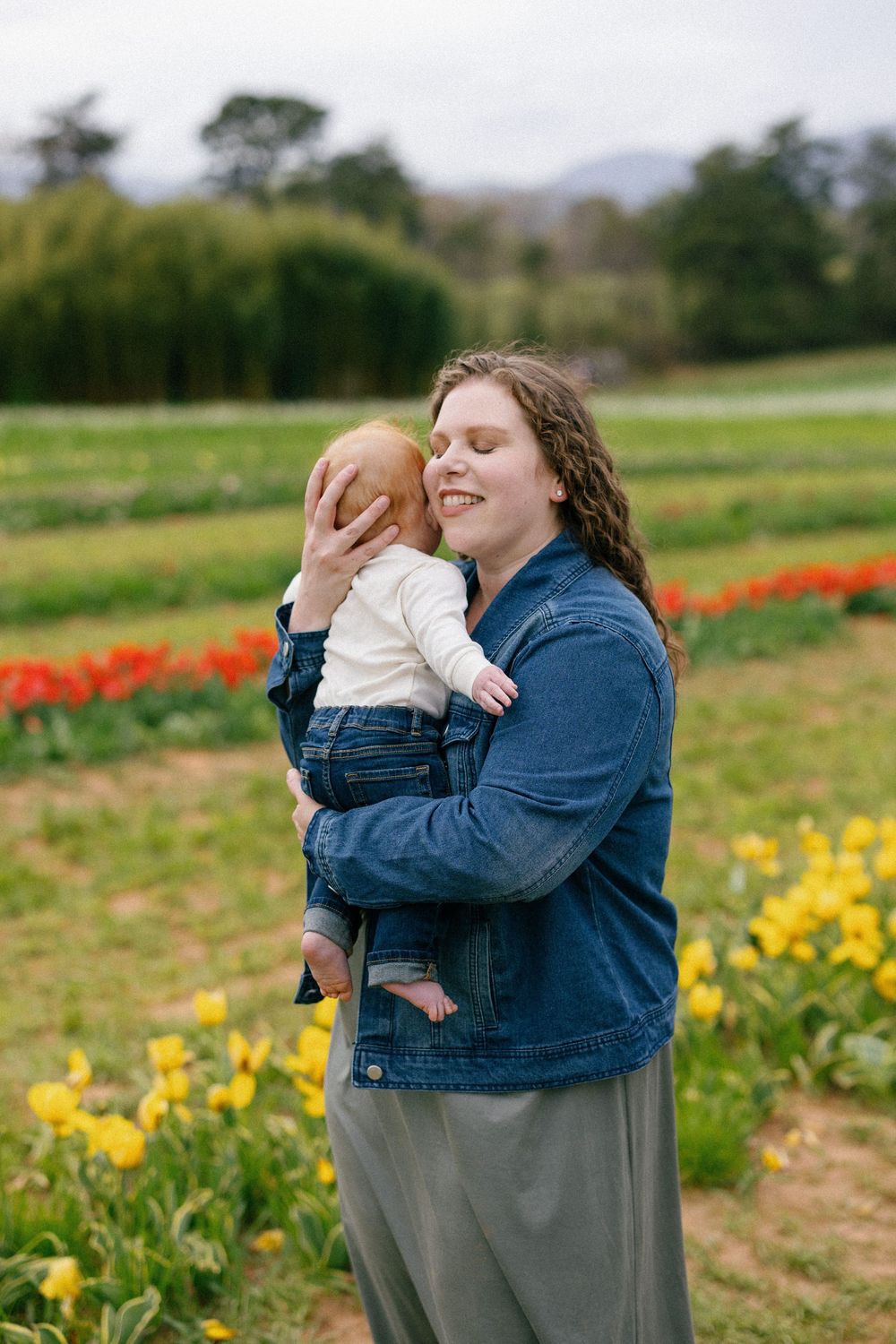 Intimate family moments captured in a tulip field with yellow and red flowers blooming in the background.