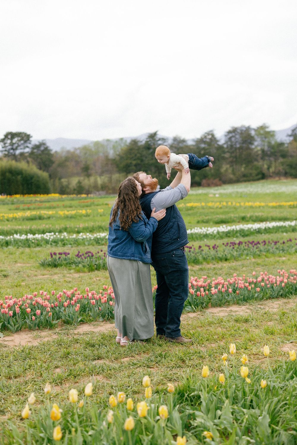 Family enjoying a spring day together in a blooming tulip field with mountains in the background.