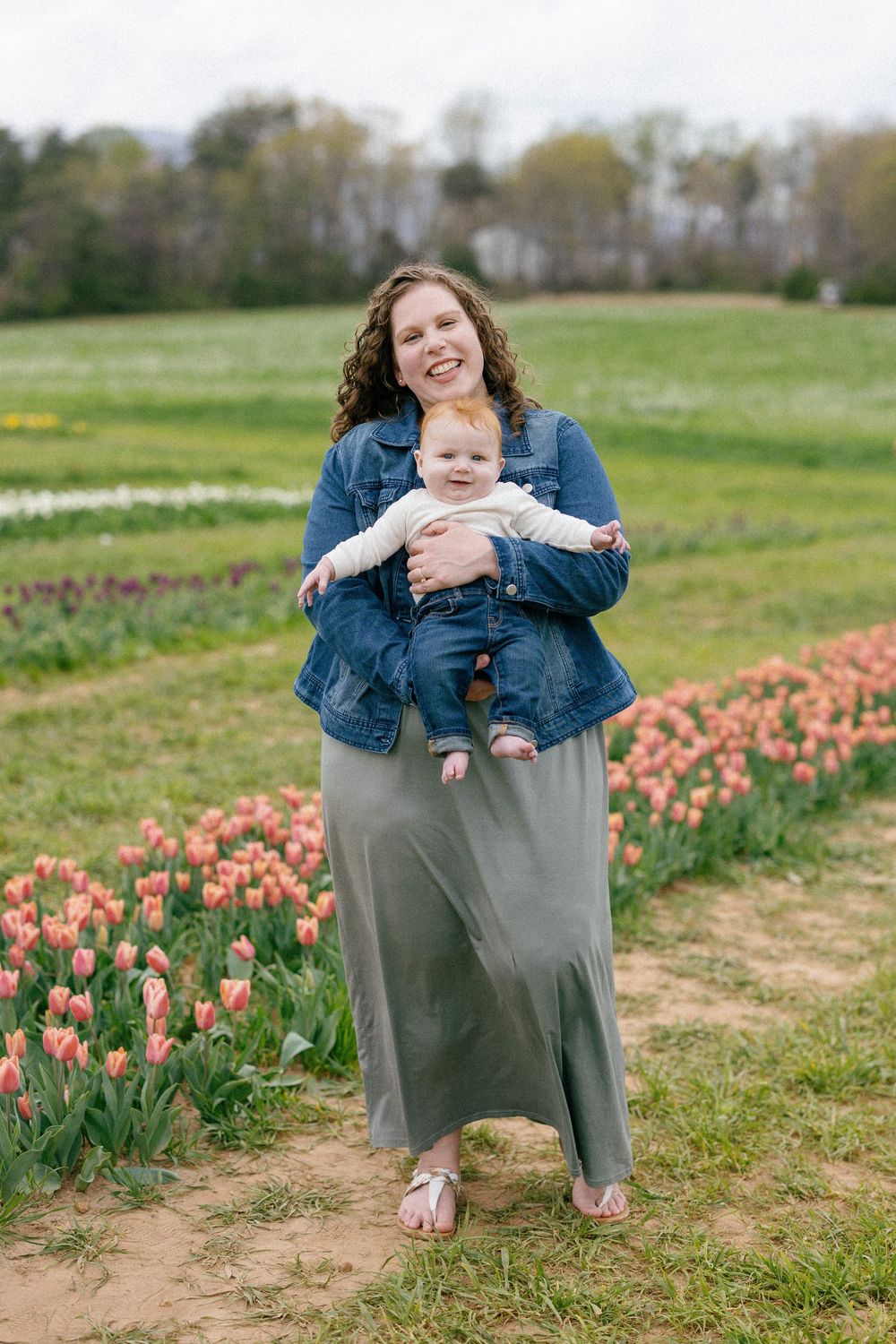 A springtime portrait taken in a field of blooming tulips with colorful flowers dotting the green pasture.
