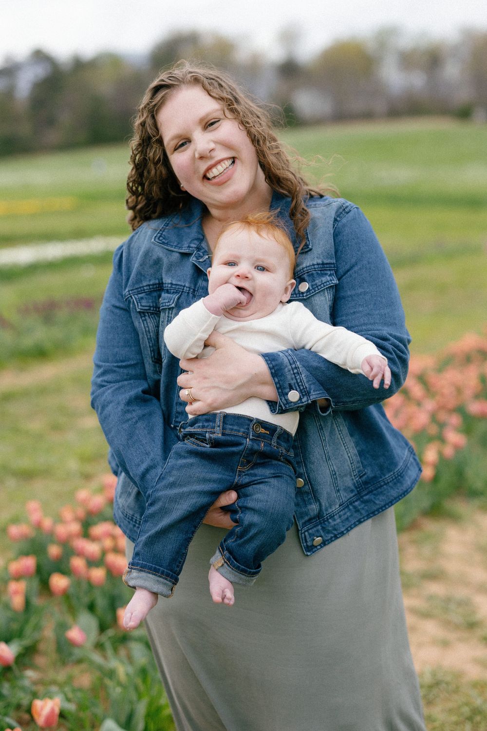 A parent and baby sharing a joyful moment together in a tulip field while wearing matching denim outfits.