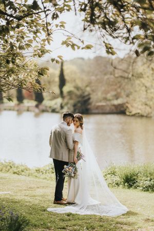Wedding couple shares intimate moments by a serene lake at Elsham Hall - image captured by Grimsby photographers.