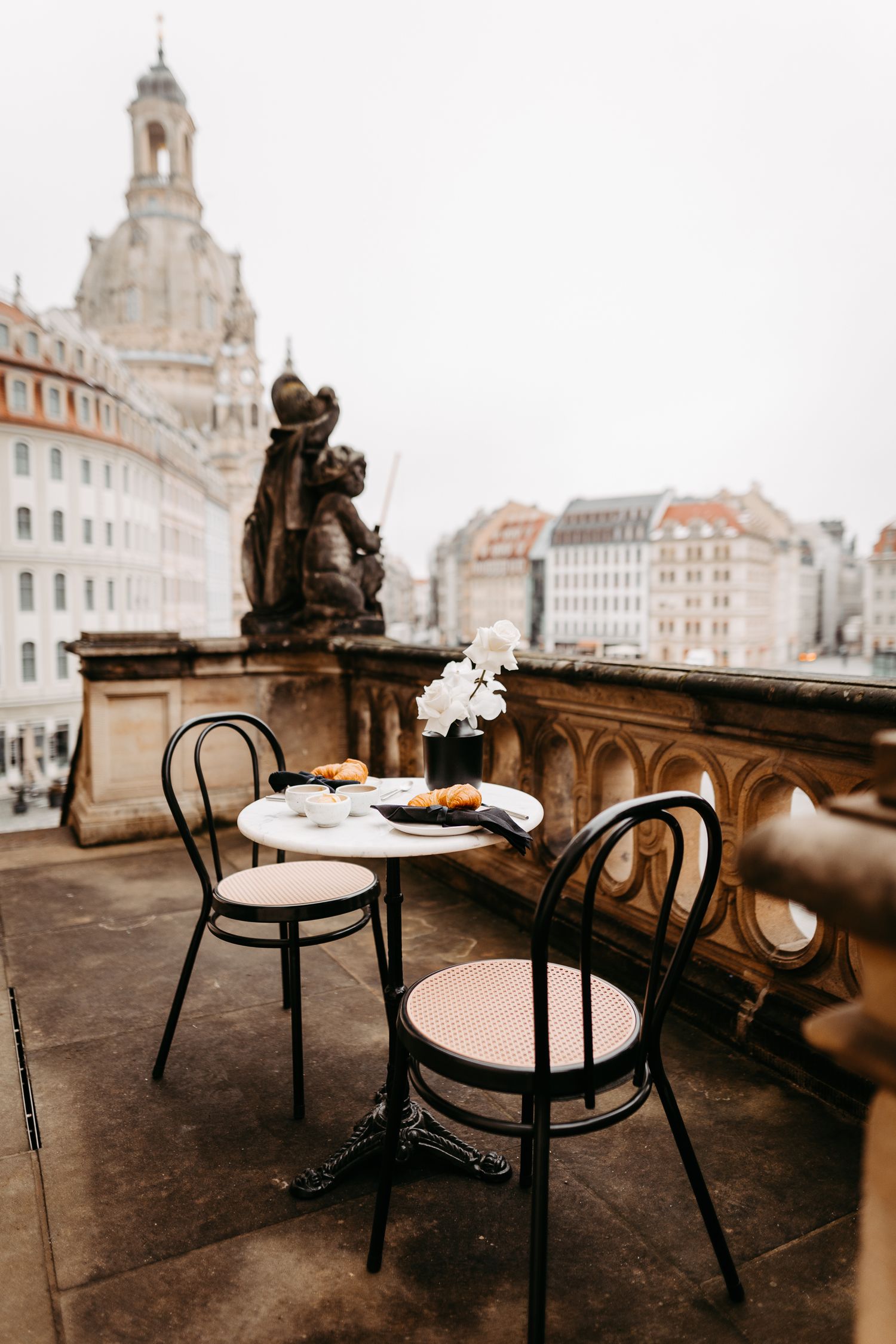 Cozy cafe table with chairs overlooking historic Dresden architecture and the famous Frauenkirche cathedral dome.