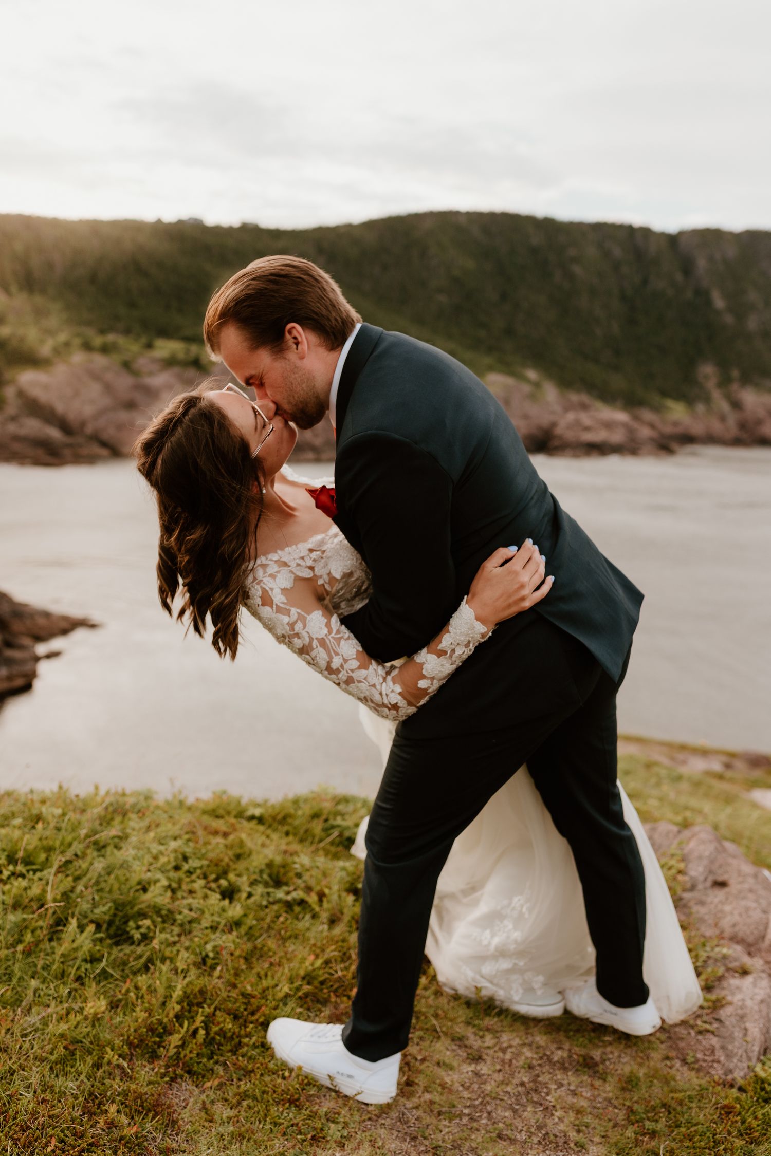 bride and groom kissing after reading their vows, groom is dipping the bride, on a Newfoundland Cliff