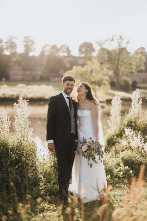 A couple shares a joyful moment in a sunlit field surrounded by delicate wildflowers during their wedding celebration.