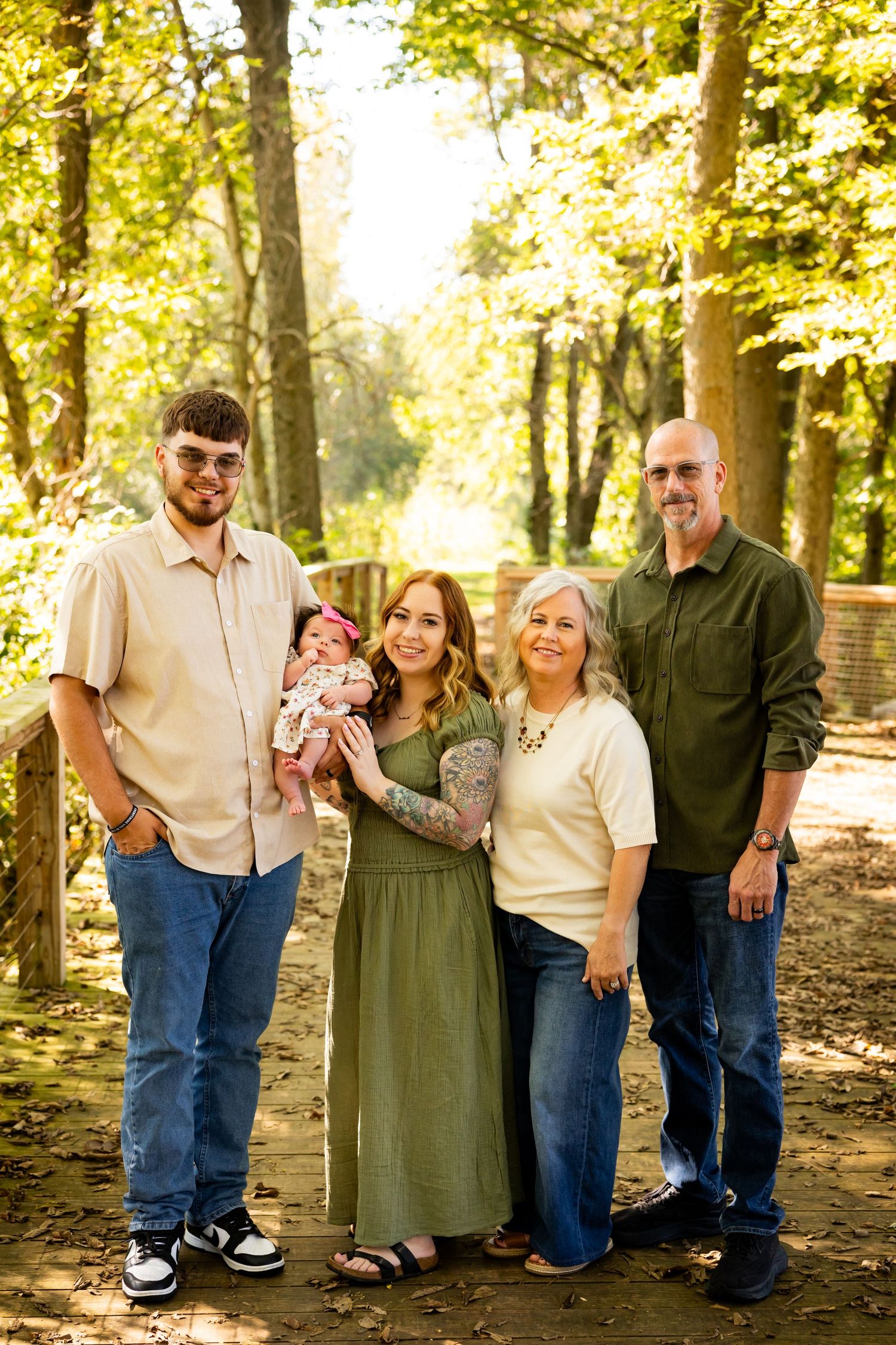 A group stands together in a wooded outdoor setting with golden sunlight filtering through autumn trees.