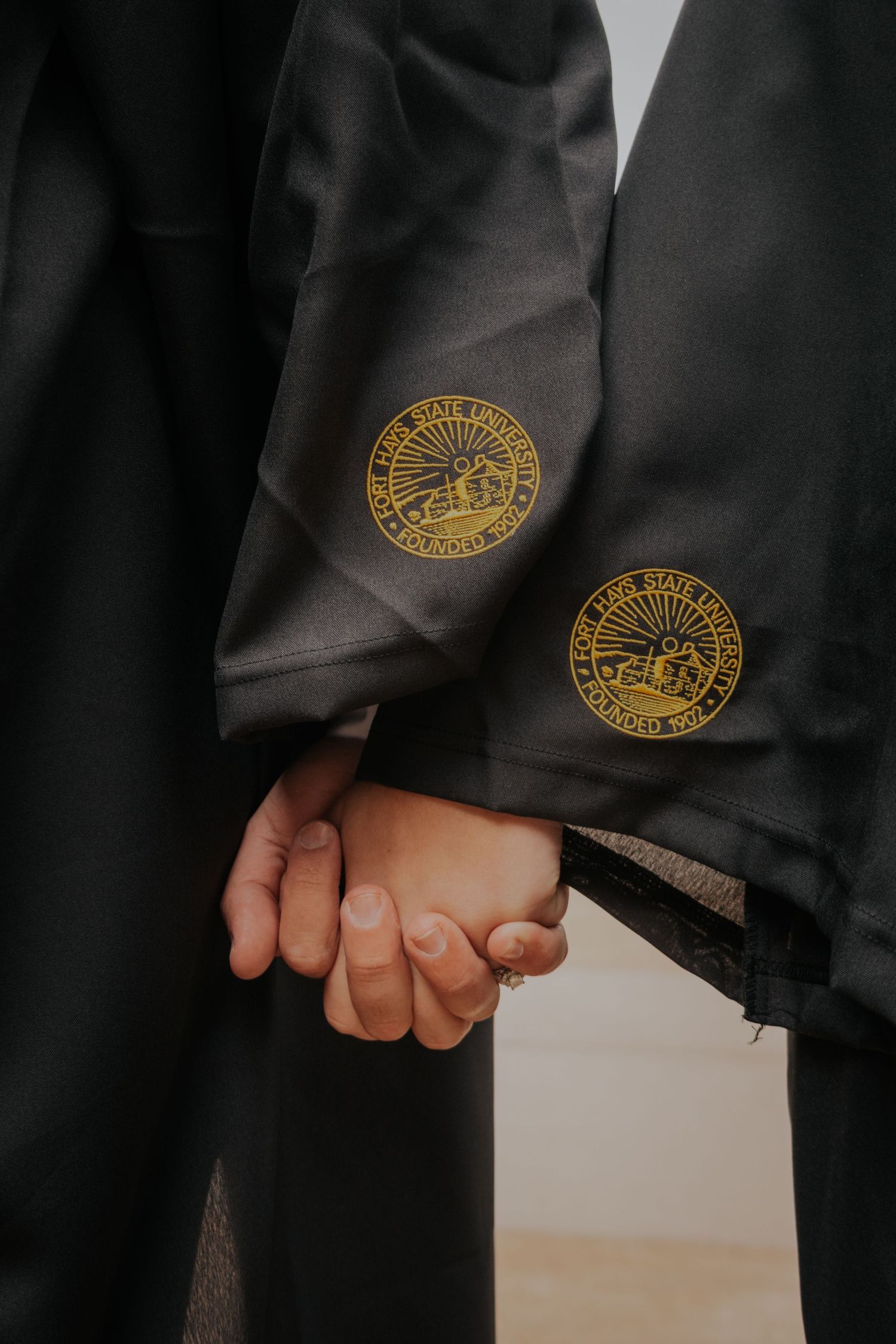 Close-up view of FFA members' hands clasped together showing their gold FFA emblems on black jackets.