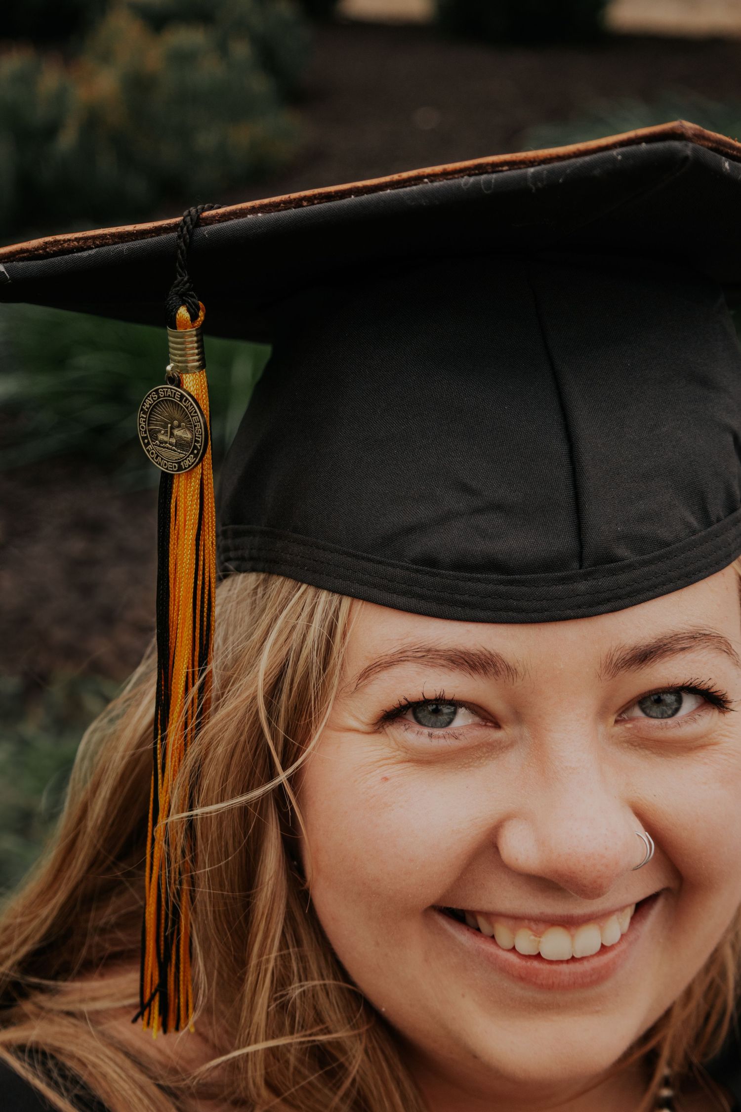 A graduation portrait series showing a graduate wearing a black cap with gold tassel against a dark outdoor background.