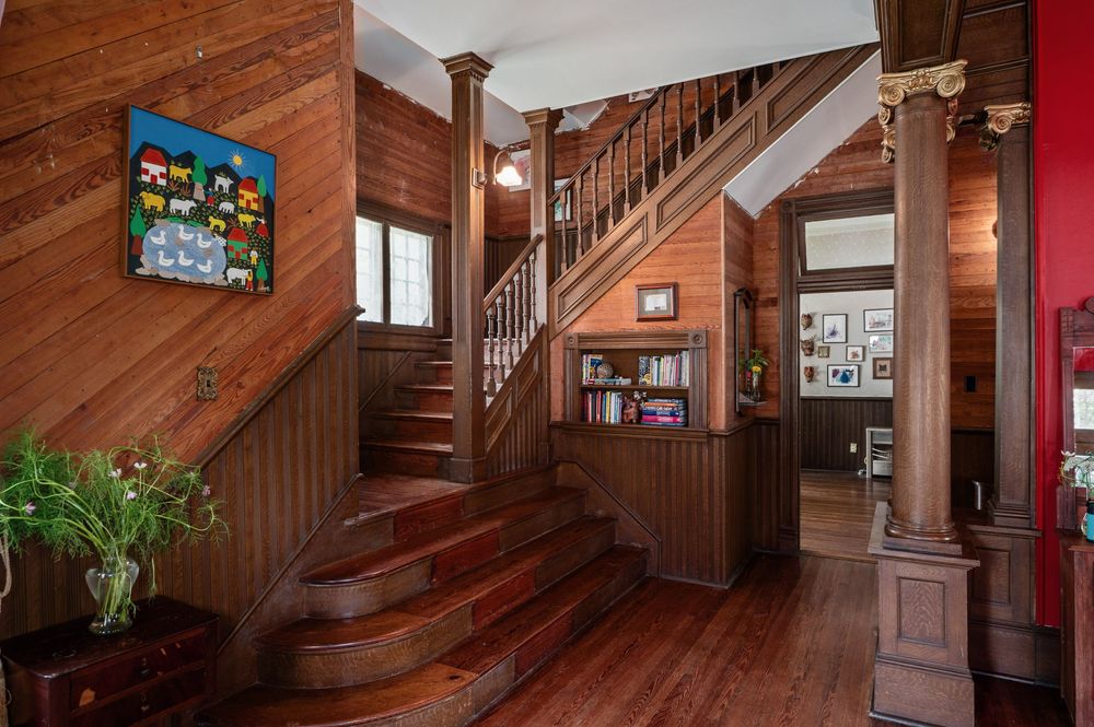 Elegant wooden staircase with ornate carved railings and warm lighting in a Victorian-style home interior.