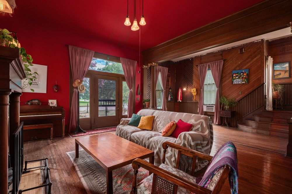 Cozy rustic cabin interior features exposed wood beams, hardwood floors and warm pendant lighting.