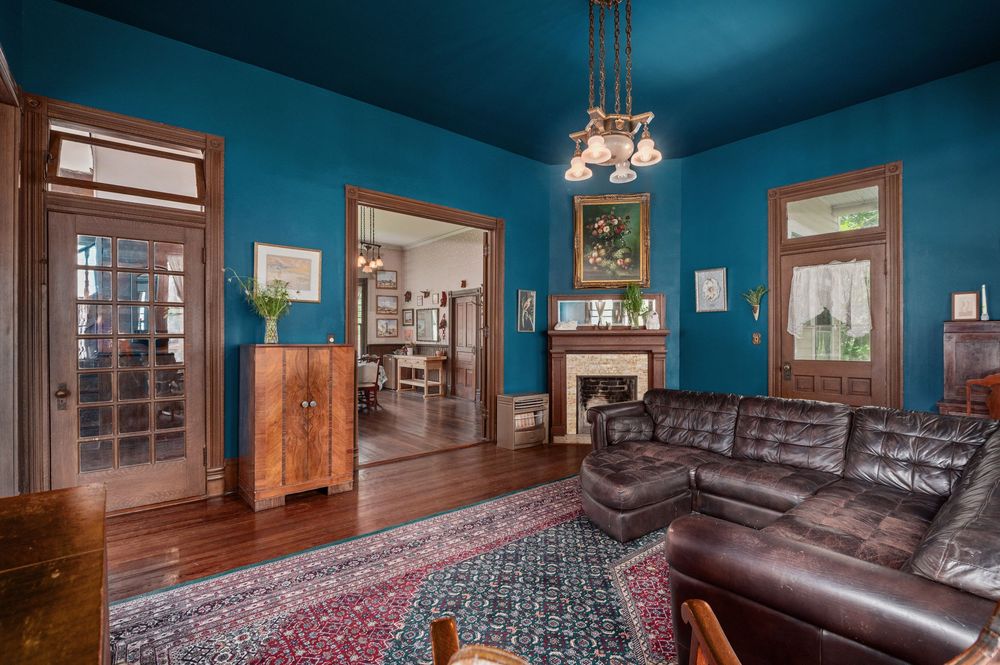 Craftsman style living room interior with teal blue ceiling, hardwood floors, period woodwork, and built-in cabinets.