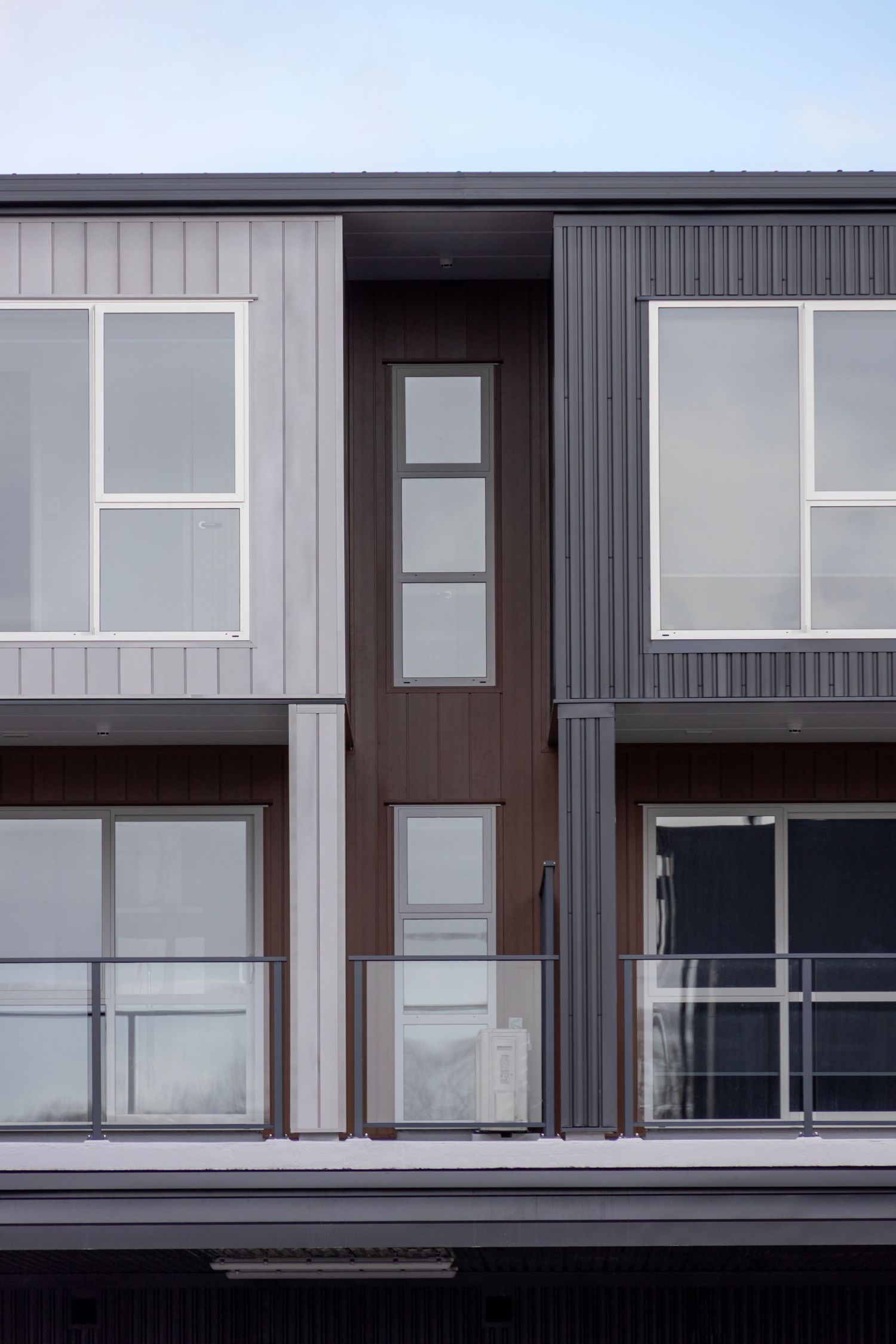 Contemporary apartment facade with panelled cladding and layered glazing.