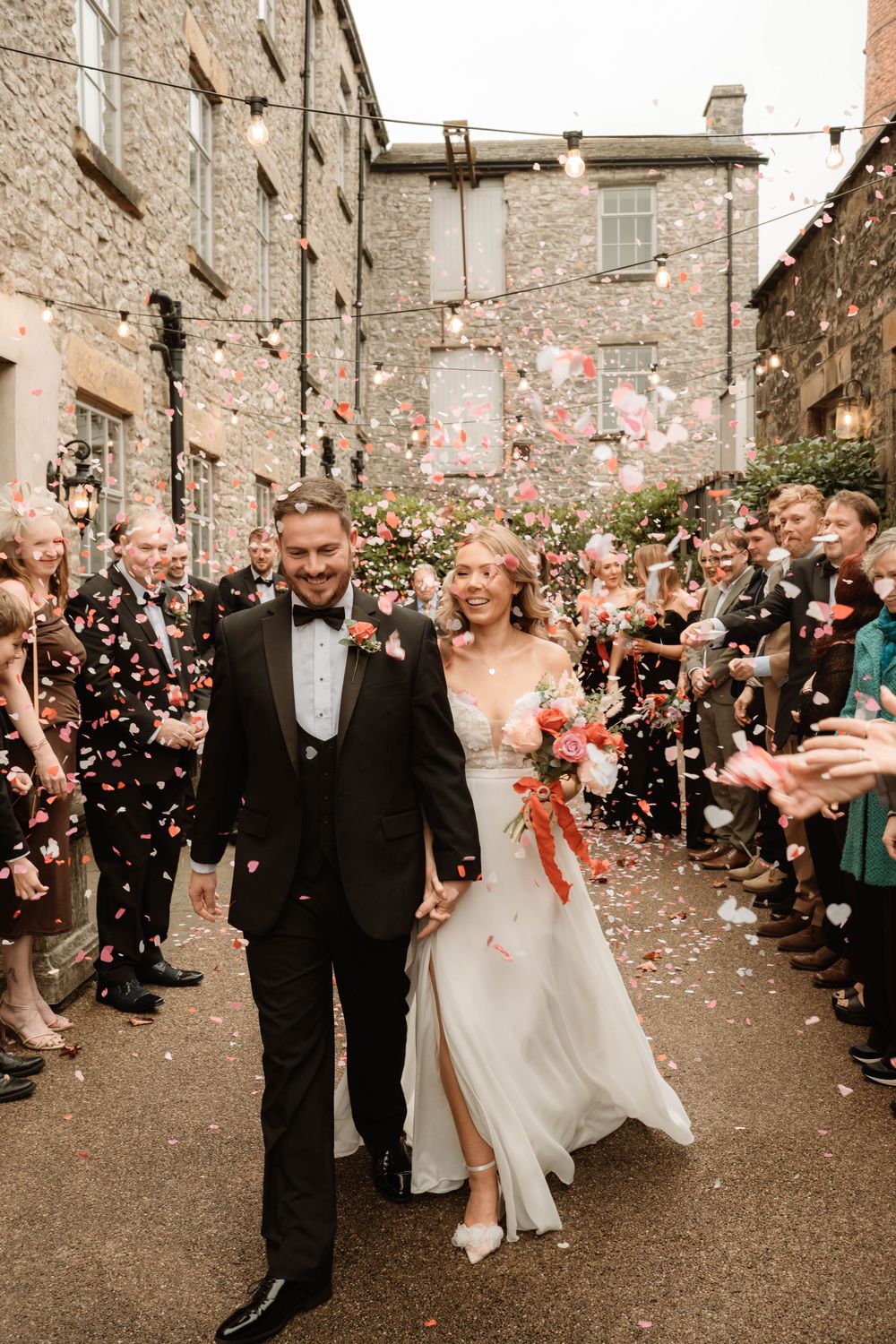 Bride and groom celebrating with confetti at industrial venue, editorial-style Manchester wedding photographer capturing real moments