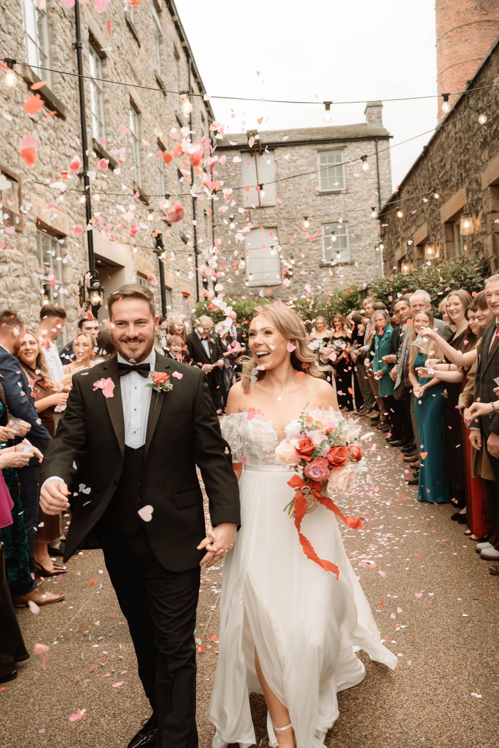Bride and groom celebrating with confetti at industrial venue, editorial-style Manchester wedding photographer capturing real moments
