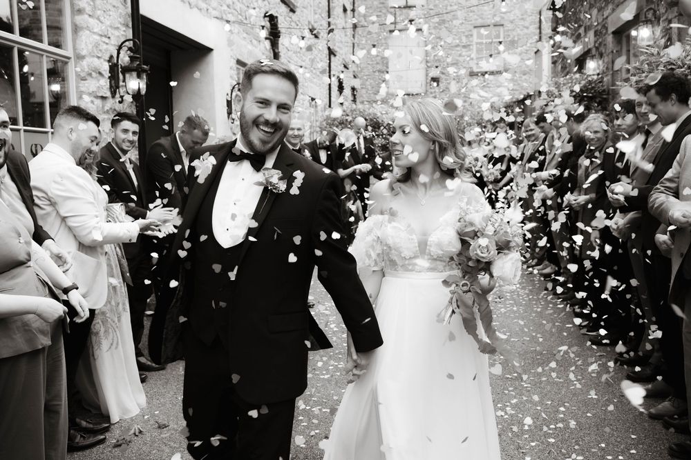 Bride and groom walking through confetti tunnel at Holmes Mill wedding, candid documentary-style shot by Manchester wedding photographer.