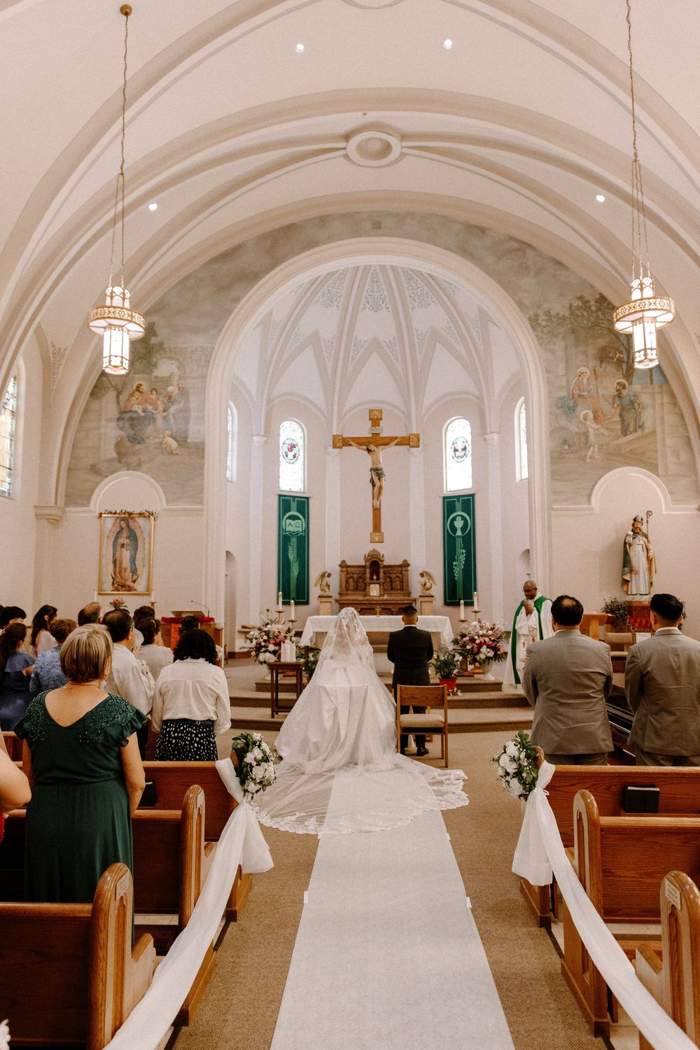 A traditional church interior with wooden pews and vaulted white ceilings during a religious service.