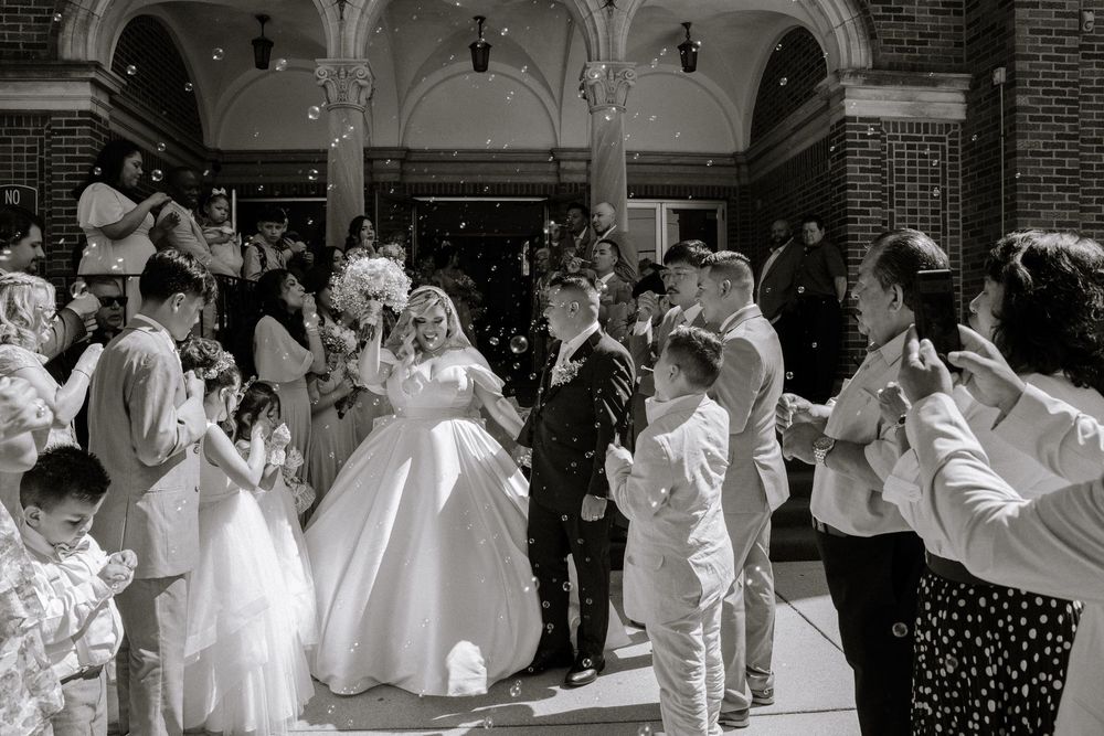 Bridal party celebrating in white and lavender dresses outside a white church.