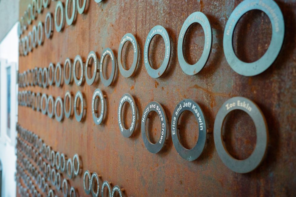 Rusty metal wall art featuring rows of circular steel rings of varying sizes as an industrial decorative installation.