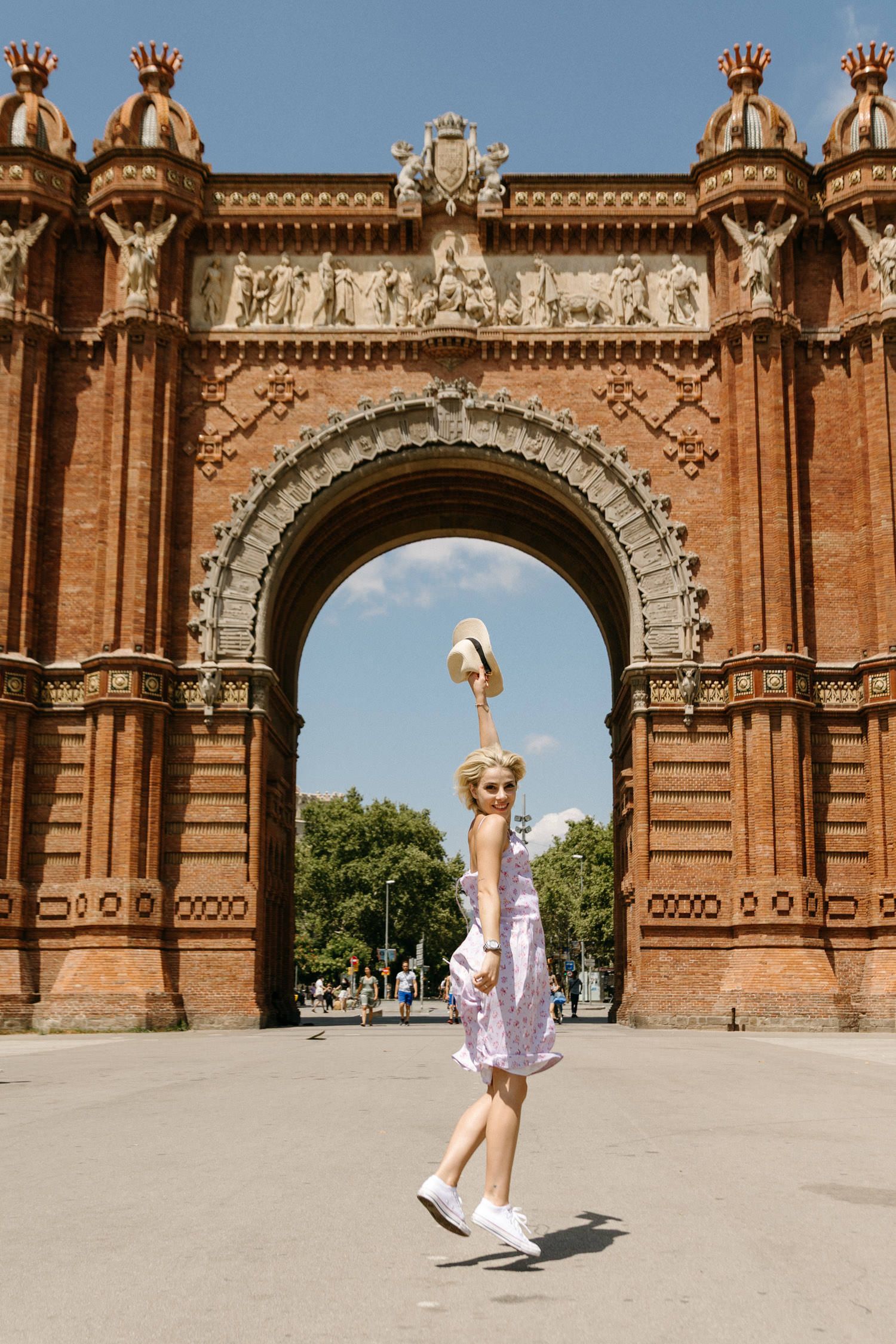 Energetic dance movements captured in front of the ornate Arc de Triomf in Barcelona.