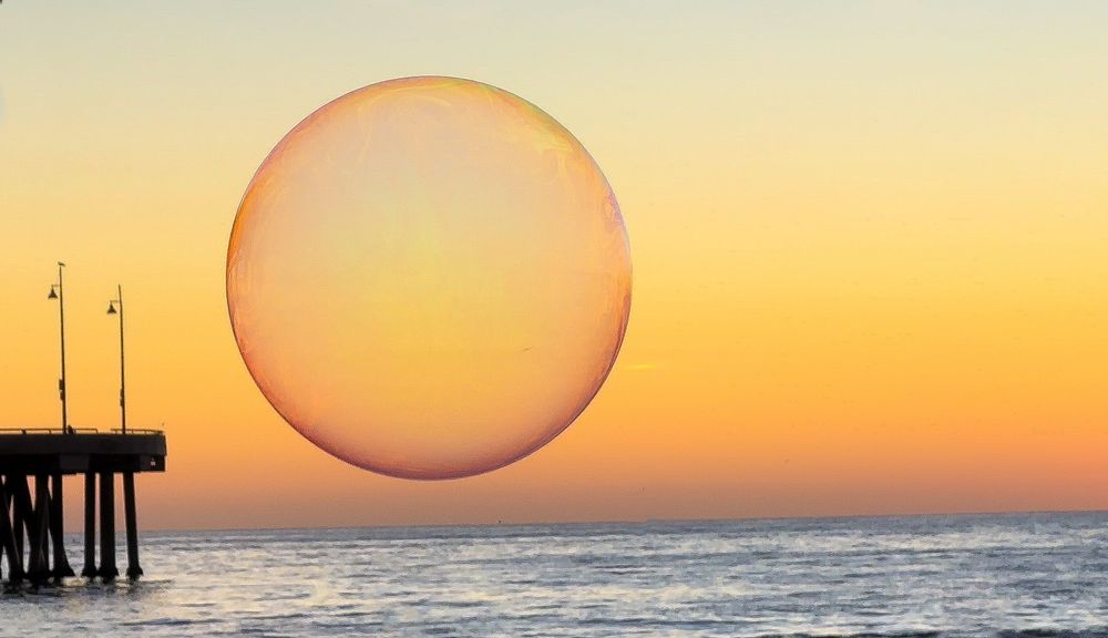 Large pink bubble appears to hover over ocean at Venice pier during golden sunset.
