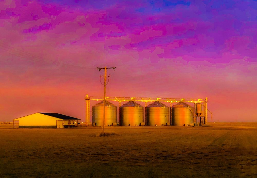 Industrial oil field silhouettes against a magenta and purple sunset sky with storage tanks visible.