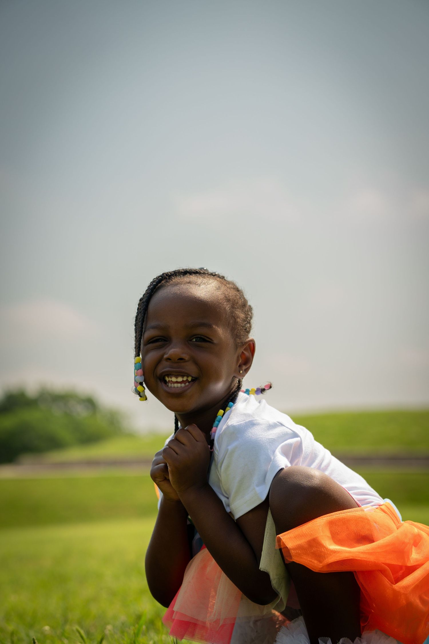 A joyful child plays in a grassy field while lying down and wearing an orange accessory.