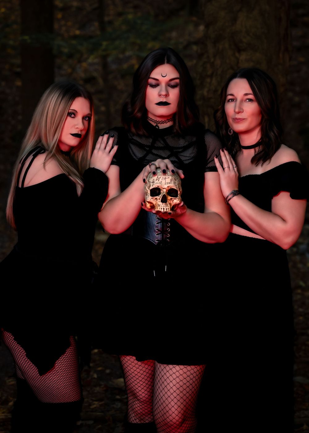 Dark and moody fashion photoshoot featuring models in black outfits posing dramatically against a dark background.