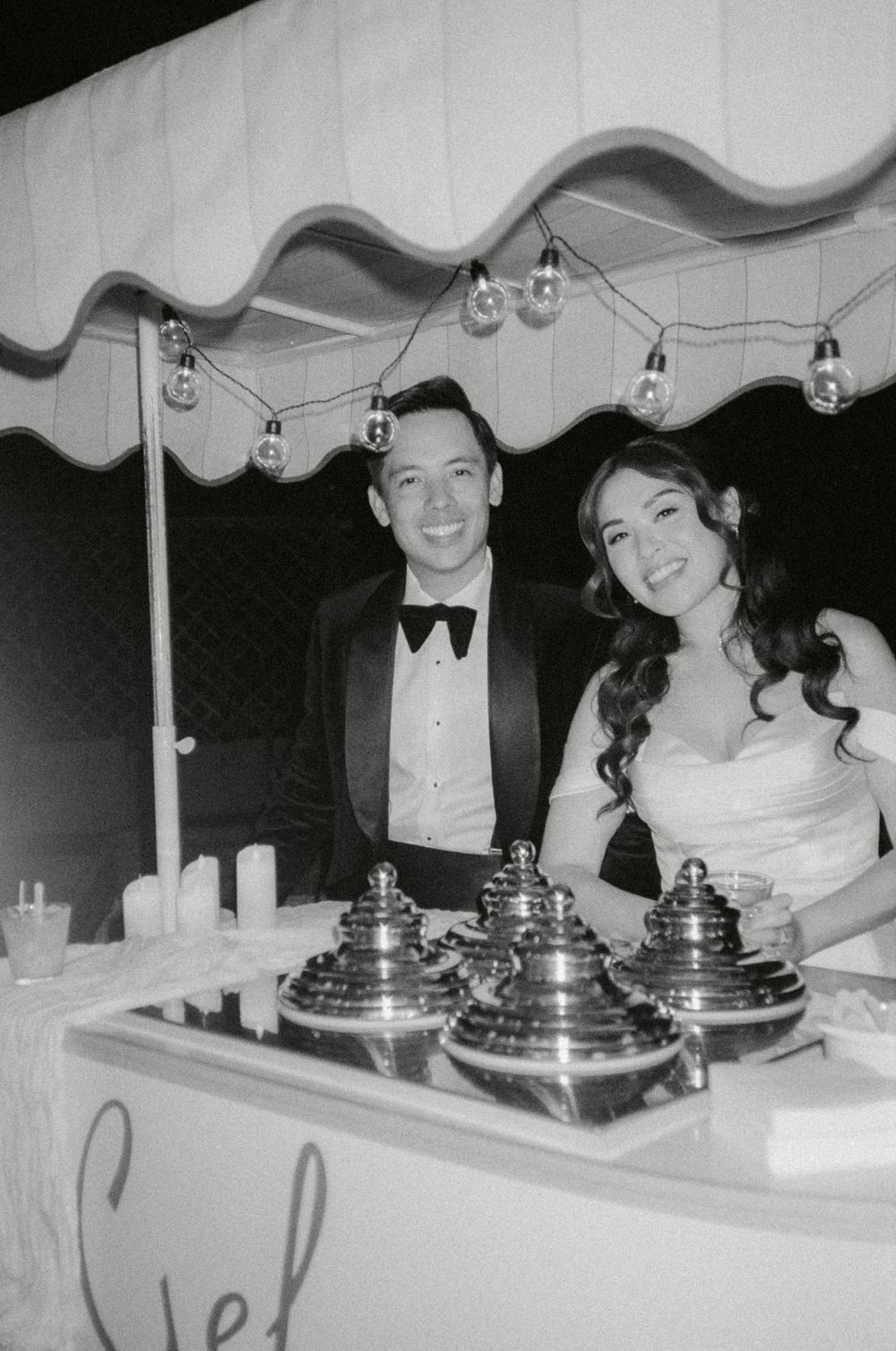 Black and white photo of guests enjoying a formal dinner service under an elegant tent. Tuscany Wedding Photographer