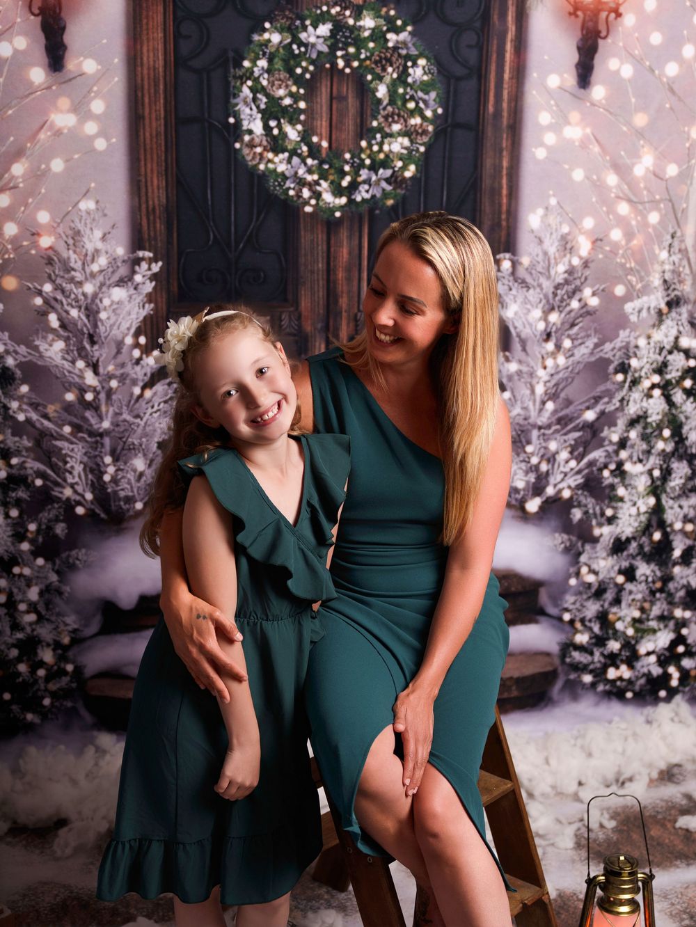 Heartwarming holiday portrait with emerald green dresses against a snowy Christmas backdrop with twinkling lights.