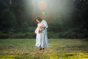 Romantic couple posing in field with sunlit background creating dreamy atmosphere.