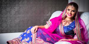 Woman in colorful traditional Indian attire poses for bridal portraits.