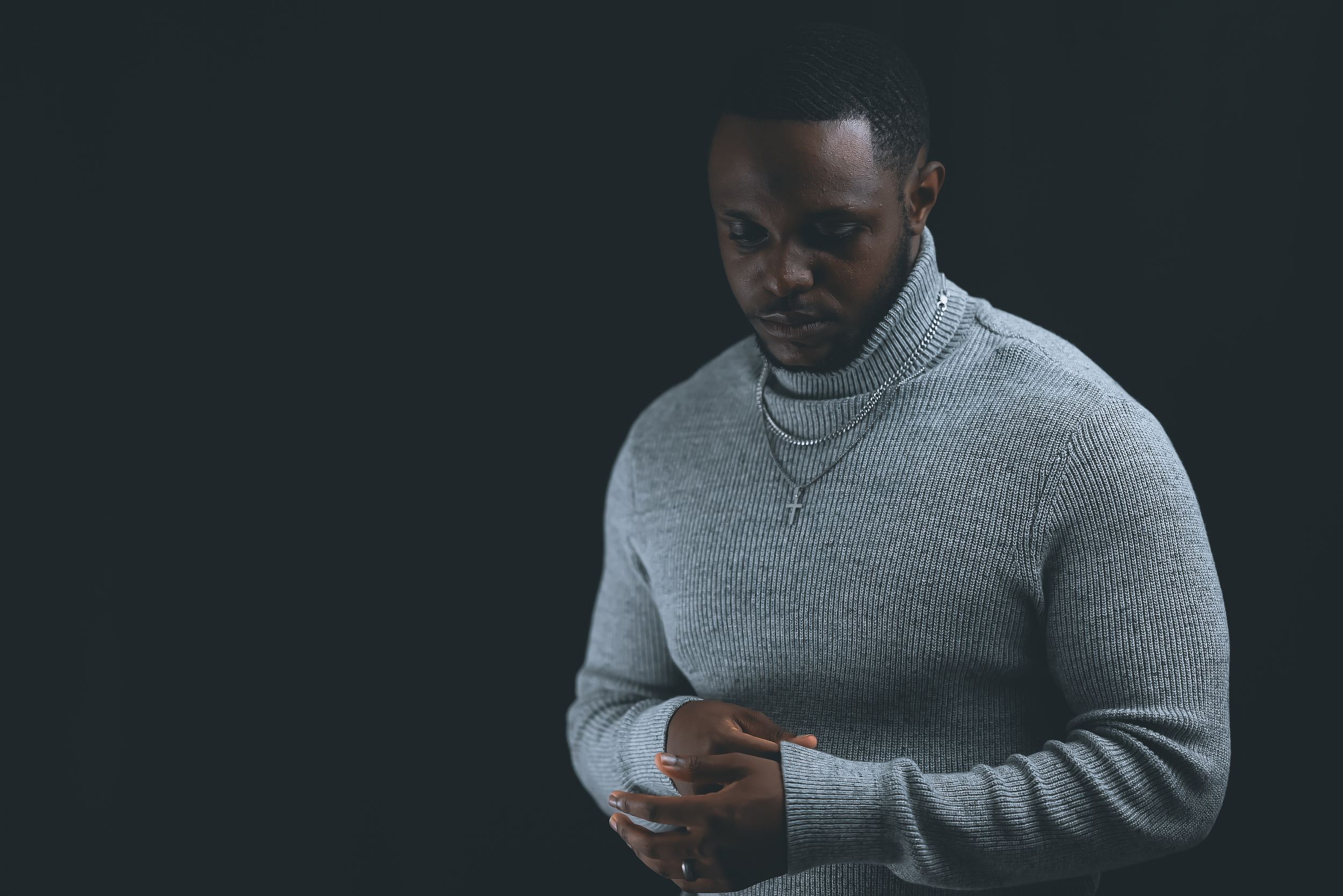 Person wearing a grey sweater checks their mobile phone in dark lighting conditions.