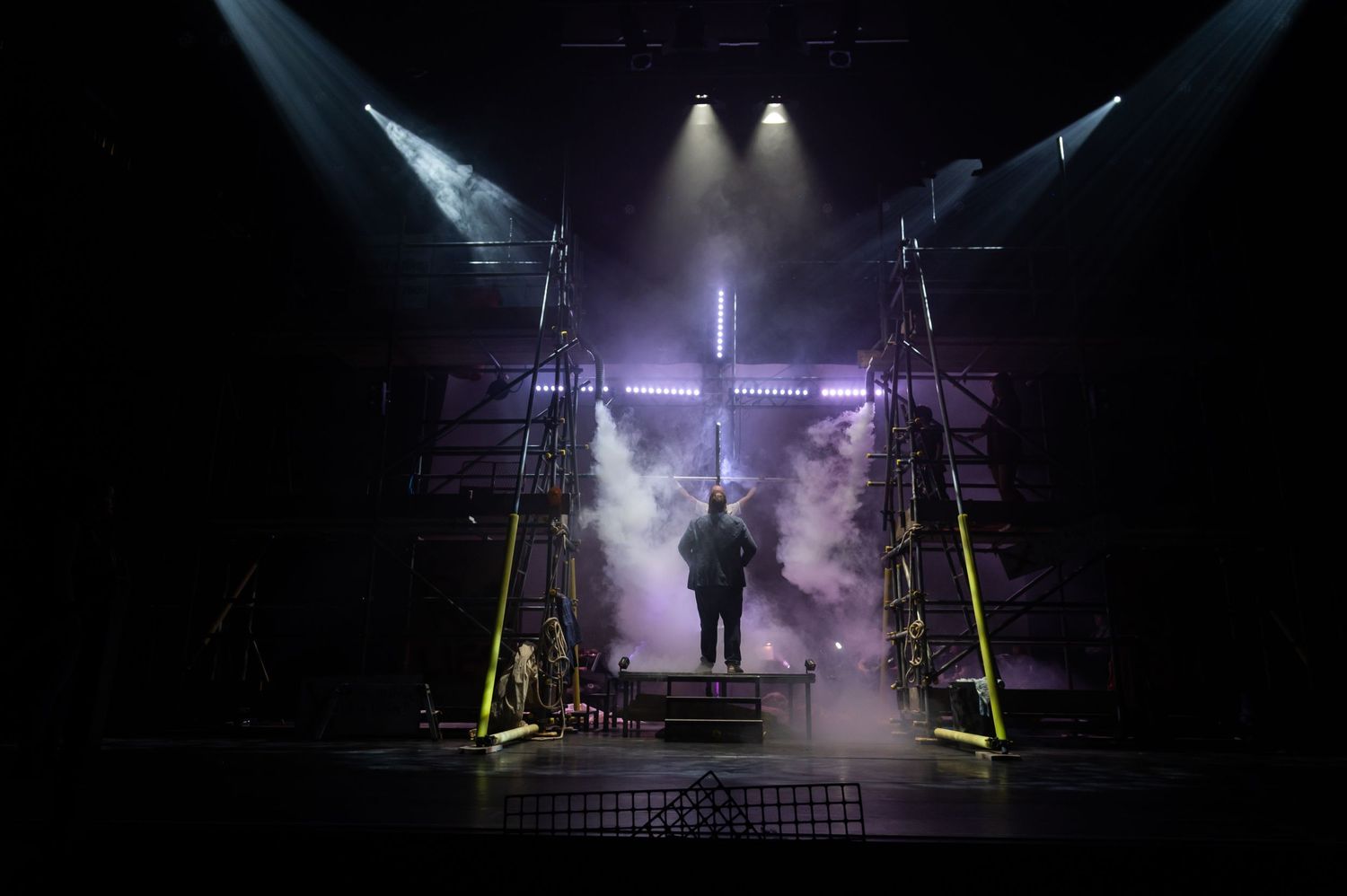 Concert stage setup illuminated by purple spotlights creating a mystical atmosphere.