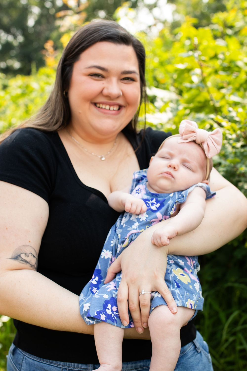 Mother and baby in floral outfit sharing joyful moments outdoors on sunny day.