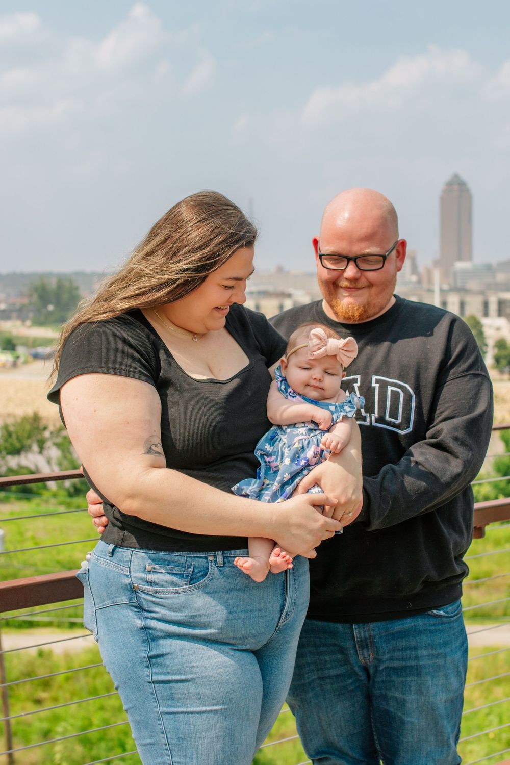 Family sharing tender moments with baby against urban skyline backdrop.