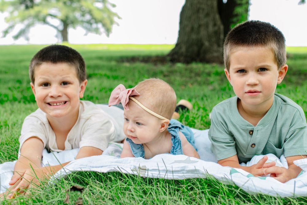 Children lying on grass during outdoor family photo session.